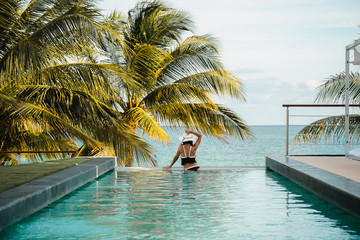 Woman relaxing in infinity swimming pool looking at view. Luxury resort. Beautiful destination...