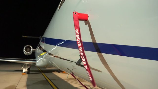 Closeup of a 'Remove Before Flight' tag installed on an ice detector vane of an Embraer 135 aircraft parked during night time