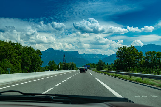 View of the road with cars, signposts and Alps mountains on the road towards the town of Annecy.Haute-Savoie in France.