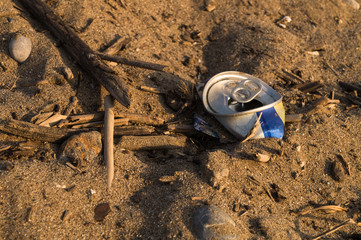 Metallic can trash on the beach.