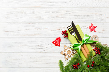 Top view of christmas decorations on wooden background. Fork and knife on napkin tied up with ribbon and empty space for your design. New year pattern concept