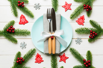 Top view of cutlery and plate on festive wooden background. New Year family dinner concept. Fir tree and Christmas decorations