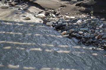 Strong water flow of a mountain river near a rocky shore