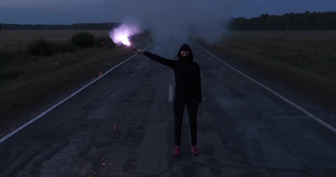 Girl with closed face, alone on highway with burning smoke bomb, looking forward, stern look, determination, courage, willingness to fight, sparks fly out of flame, violet flame, metaphor of struggle