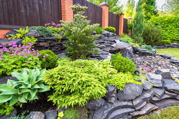 Landscape design of home garden. Beautiful stone landscaping in backyard in summer.