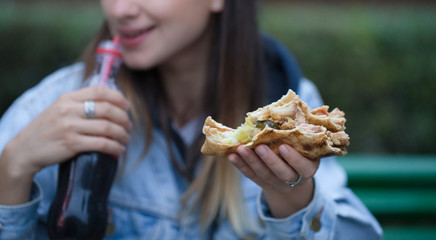 Young woman eating fast food on the street.