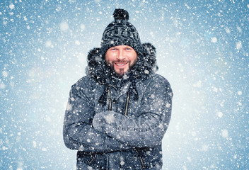 Fototapeta na wymiar Smiling happy bearded man in winter clothes warms his hands, cold, snow, frost, blizzard