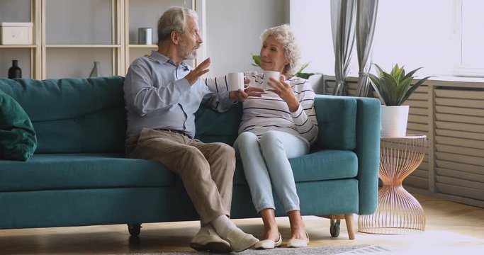 Retired senior couple talking drinking tea in living room together