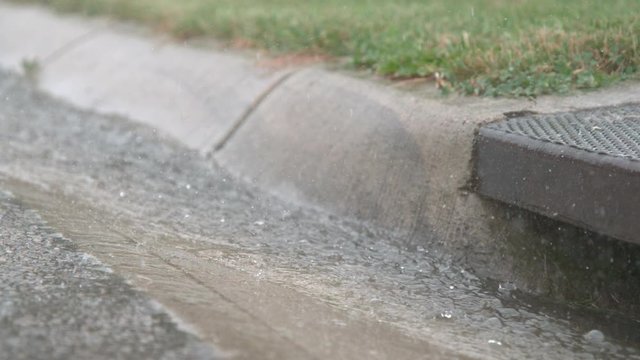 Water on street going down into sewer drain slow motion