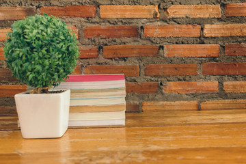 Old books on Wooden table in front Brick wall background