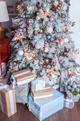 White decorated Christmas tree with many gifts underneath in gentle pastel colors. Good New Year spirit