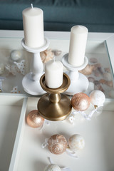 Three Stylish white large candles on the table, and New Year's balls, photos in gentle pastel colors. Christmas mood