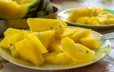 Yellow watermelon cut into saucers on a table.
