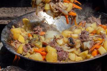 Beef with vegetables cooked in a wok on fire in a mobile kitchen. Against the backdrop of a ladle.