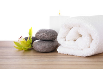 Obraz na płótnie Canvas Fresh towel, spa stones and exotic flower on wooden table against white background