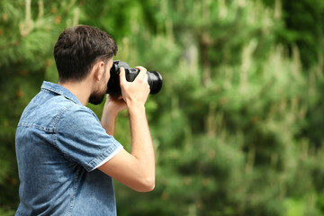 Photographer taking photo with professional camera in park. Space for text