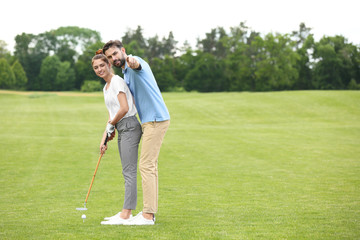Coach teaching woman to play golf on green course