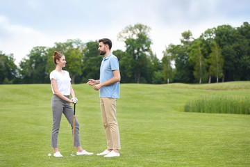 Coach teaching woman to play golf on green course