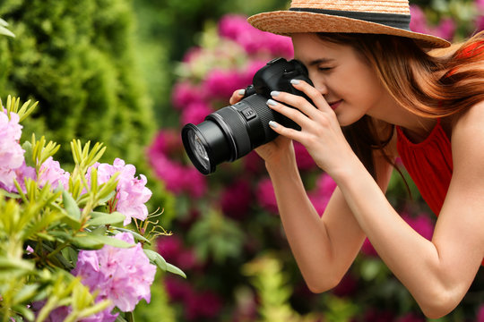 Photographer taking photo of blossoming bush with professional camera in park