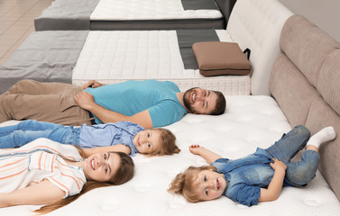 Happy family lying on new orthopedic mattress in store
