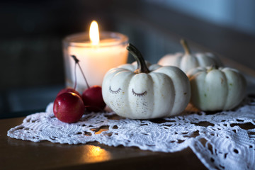 autumn and winter cozy table decoration with candle, small apples and white baby boo pumpkins