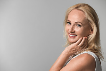 Portrait of beautiful mature woman with perfect skin on grey background. Space for text