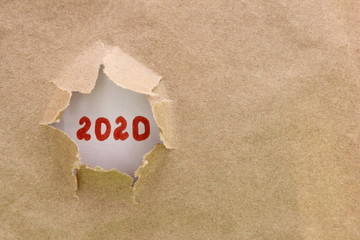 Ripped or torn brown paper revealing new year 2020 on white background. Copy space.