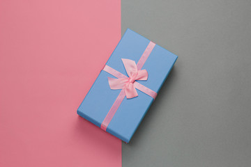 top view blue gift box with festive pink bow on a gray background with pastel pink frame with free space for text