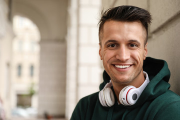 Portrait of handsome young man with headphones outdoors. Space for text