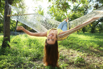 Young woman resting in comfortable hammock at green garden