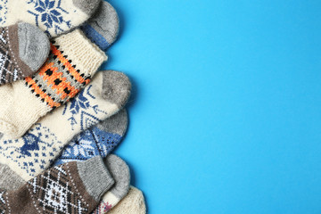 Soft knitted socks on light blue background, flat lay with space for text. Winter clothes