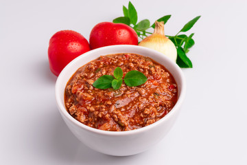 Bolognese (also know as Bolognesa or Bolonhesa) sauce in a white bowl isolated in white background, soft light, studio photo, copy space