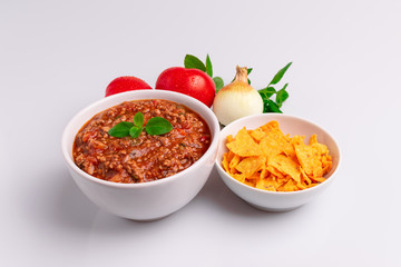Bolognese (also know as Bolognesa or Bolonhesa) sauce and corn chips nachos in a white bowl isolated in white background, soft light, studio photo, copy space