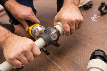 Soldering iron for a plastic water pipe close-up. Hands plumbers hold pipes.