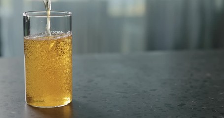 Slow motion pour pear cider into glass on terrazzo countertop with copy space