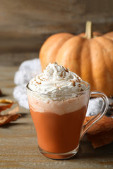 Obraz na płótnie Canvas Pumpkin spice latte with whipped cream in glass cup on wooden table