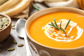 Delicious pumpkin soup in bowl on table, closeup