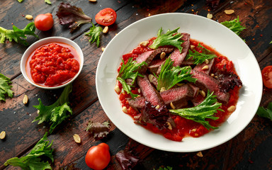 Beef Steak with Romesco sauce, nuts and vegetables on white plate
