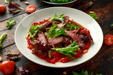 Beef Steak with Romesco sauce, nuts and vegetables on white plate