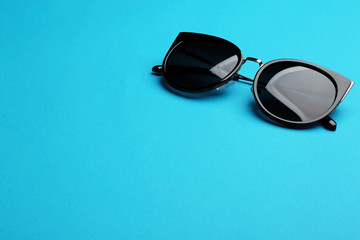 Stylish sunglasses on blue background, space for text. Fashionable accessory