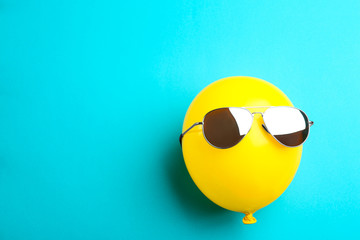 Balloon with sunglasses on blue background, top view. Space for text