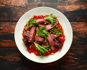 Beef Steak with Romesco sauce, nuts and vegetables on white plate