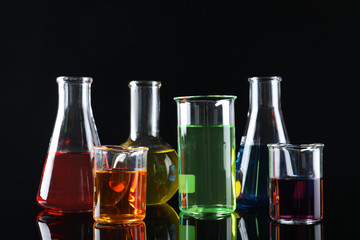 Laboratory glassware with colorful liquids on black background