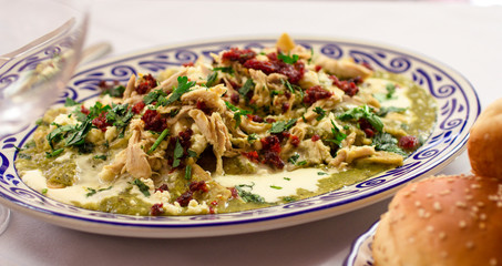 Traditional green chilaquiles with shredded chicken, served on a colorful Talavera plate—authentic Mexican food styling for editorial use.