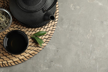 Cup and teapot of hot aromatic beverage on grey table, flat lay. Space for text
