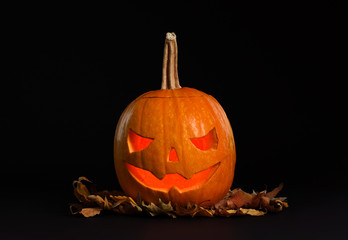 Pumpkin head with autumn leaves on black background. Jack lantern - traditional Halloween decor