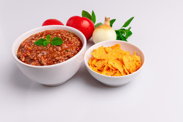 Bolognese (also know as Bolognesa or Bolonhesa) sauce and corn chips nachos in a white bowl isolated in white background, soft light, studio photo, copy space