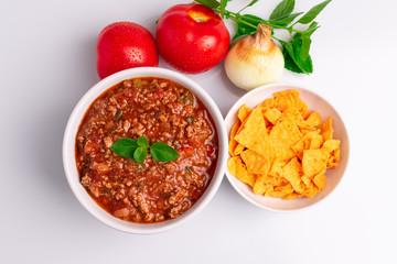 Bolognese (also know as Bolognesa or Bolonhesa) sauce and corn chips nachos in a white bowl isolated in white background, soft light, studio photo, copy space