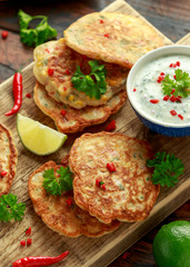Corn fritters, pancake with dip white sauce, lime and chilli on wooden board