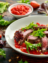 Beef Steak with Romesco sauce, nuts and vegetables on white plate
